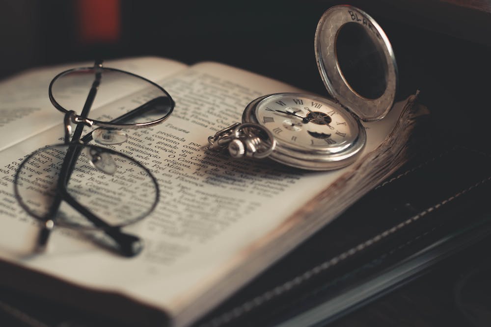 Zdjęcie starej książki, na niej okrągłe okulary i kompas