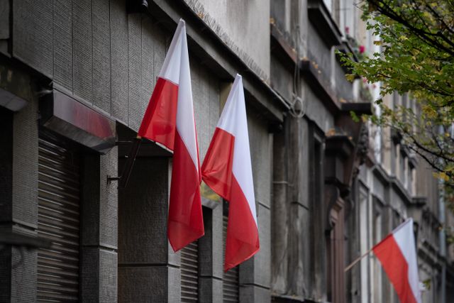 Dwie flagi Polski na tle szaregp budynku